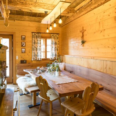 The breakfast area of the Bed and Breakfast, featuring a wooden table, benches, chairs, and a traditional green tiled stove.