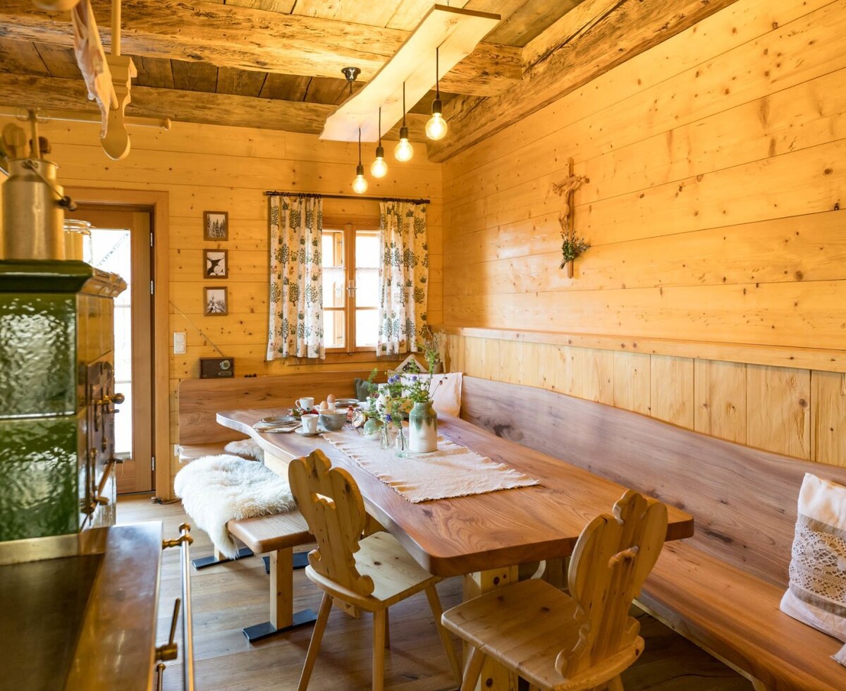 The breakfast area of the Bed and Breakfast, featuring a wooden table, benches, chairs, and a traditional green tiled stove.
