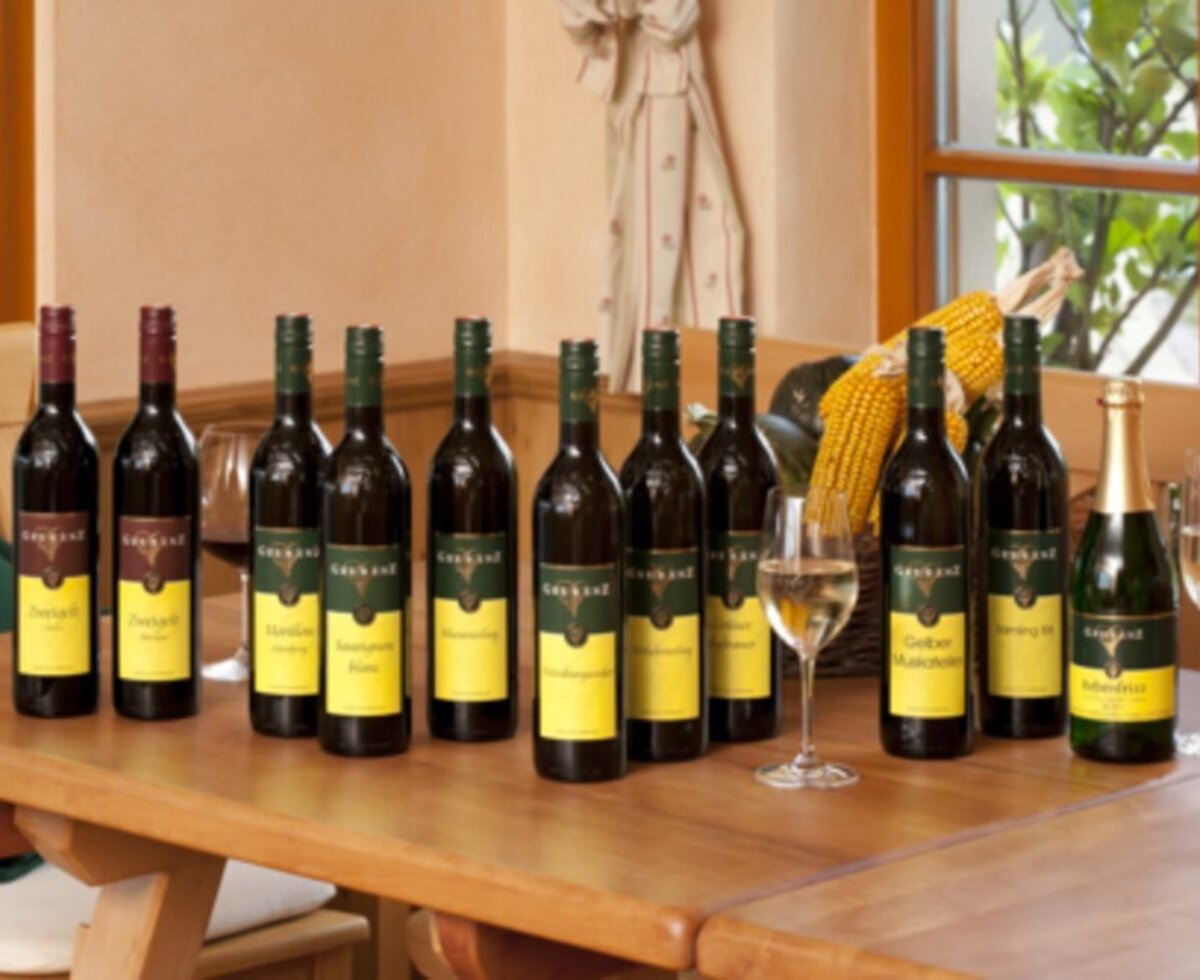 A selection of wine bottles and sparkling wine with filled glasses on a wooden table at the Hotel.