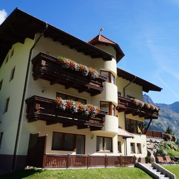 Exterior view of the farmhouse with balconies, flower boxes, and a view of the Pitztal mountains.