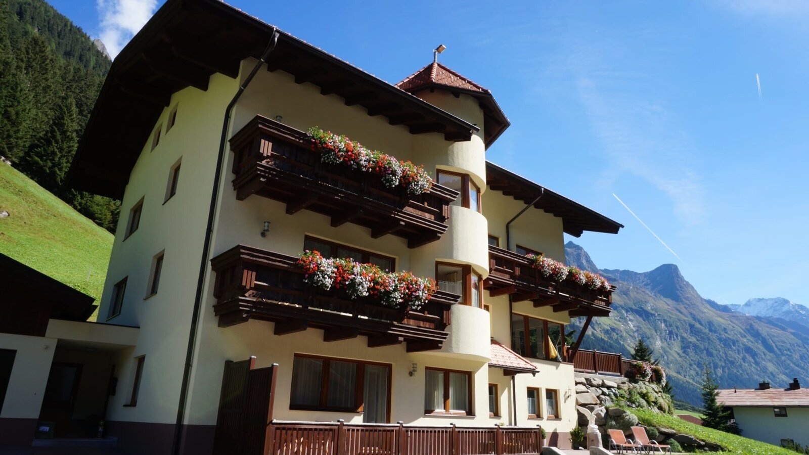 Exterior view of the farmhouse with balconies, flower boxes, and a view of the Pitztal mountains.