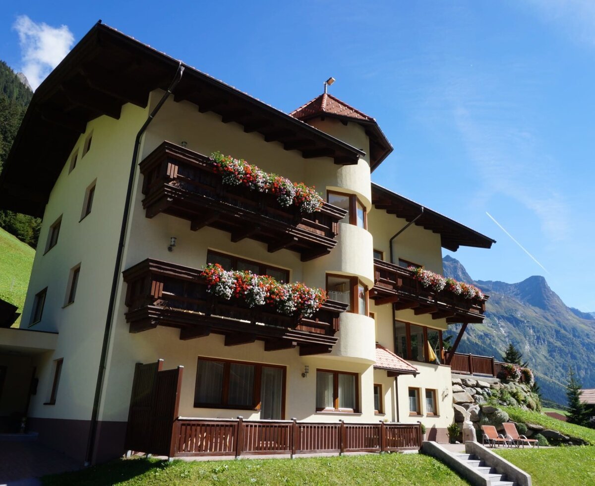 Exterior view of the farmhouse with balconies, flower boxes, and a view of the Pitztal mountains.