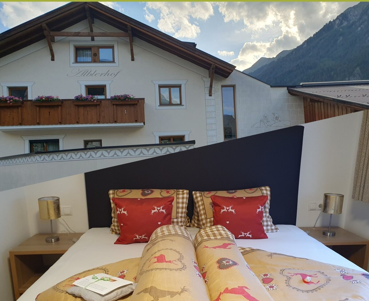 Bedroom in the Farm House with patterned bedding, bedside tables, and a view of the exterior building and mountains.