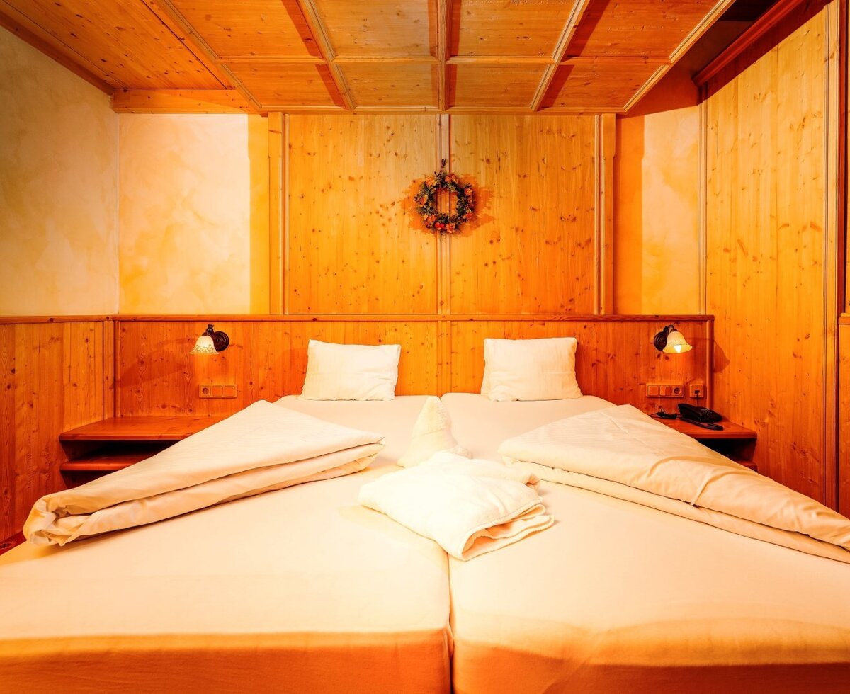 Cozy sleeping area of the Rosengarten Suite in Haus Bergheimat with warm wood design and modern comfort.
