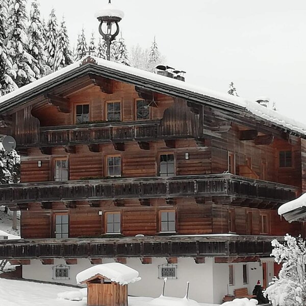 The snow-covered wooden exterior of the Farm House, featuring multiple levels and balconies.