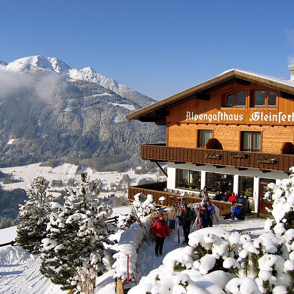 The Farm House, Alpengasthaus Gleinserhof, on a snowy mountain slope with skiers gathered at the entrance. The Farm House, Alpengasthaus Gleinserhof, on a snowy mountain slope with skiers gathered at the entrance.