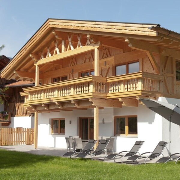 The inviting apartments featuring a wooden facade, a sunny terrace, and comfortable loungers in the green garden.