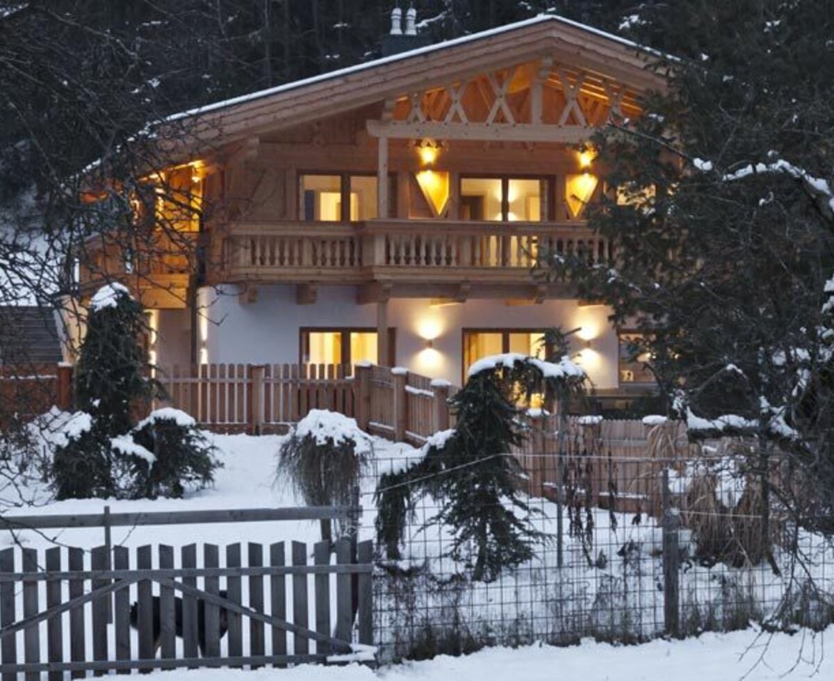 The inviting apartments building in a snowy winter landscape, warmly lit at dusk.