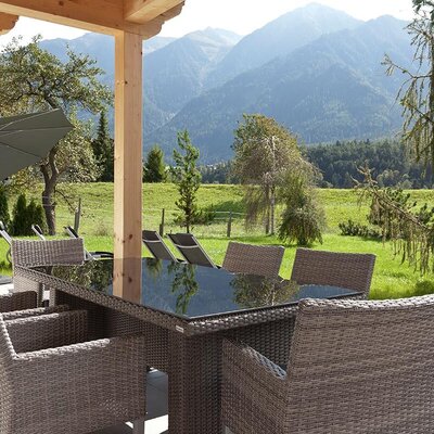 The apartment's inviting terrace features a comfortable outdoor dining area, sun loungers, and scenic mountain views.