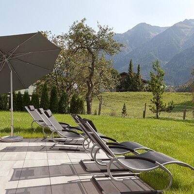 The apartments' inviting lawn area featuring comfortable sun loungers, a parasol, and scenic views of the surrounding mountains.