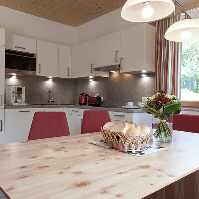 A modern kitchen-diner in the apartment featuring a light wood dining table, a cozy seating area, and a fully equipped kitchenette.