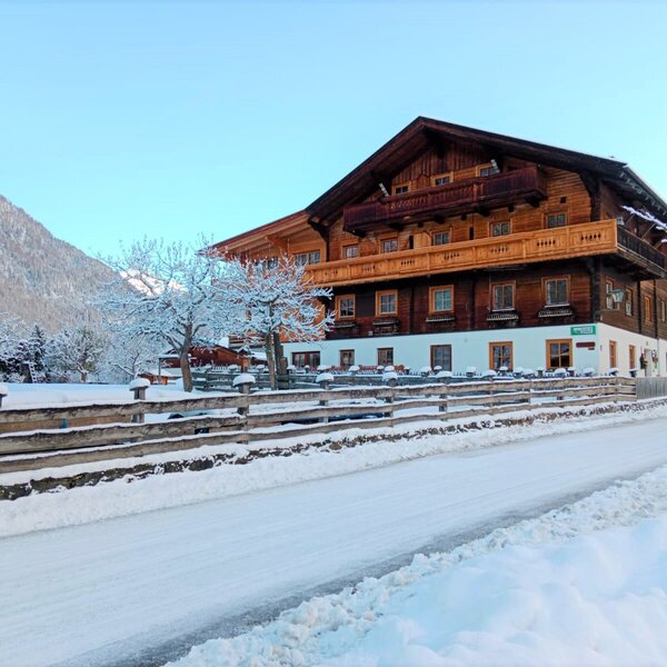 The exterior of the Farm House, a multi-story wooden building with balconies, set in a snow-covered mountain landscape.