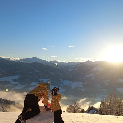 Golden hour winter views of the snowy mountains and valleys from the Farm House, with children observing the landscape.