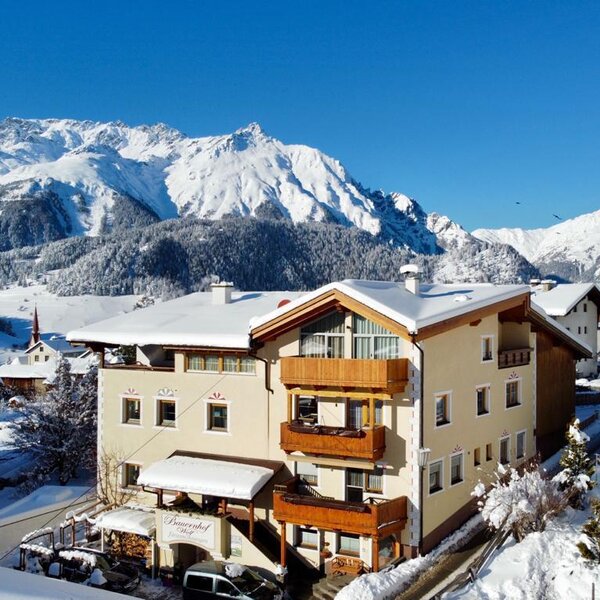 The Farm House exterior in winter, featuring balconies and surrounded by snow-covered mountains.