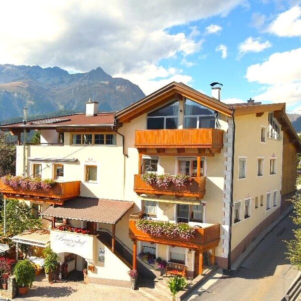 Exterior view of the farmhouse featuring balconies with flower boxes, a sun terrace, and mountain views.