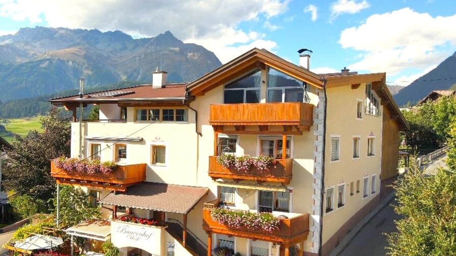 Exterior view of the farmhouse featuring balconies with flower boxes, a sun terrace, and mountain views.