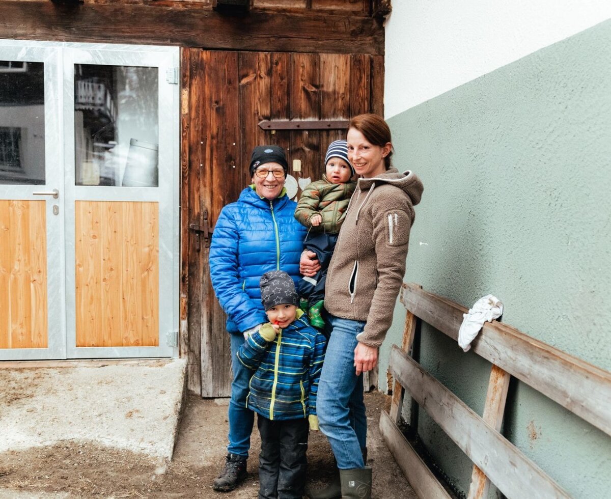 The host family of the Bergerhof Bauernhof with children in front of a farm building.