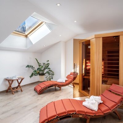 The farmhouse's inviting wellness area features a wooden sauna, comfortable lounge chairs, and plenty of natural light from a skylight.