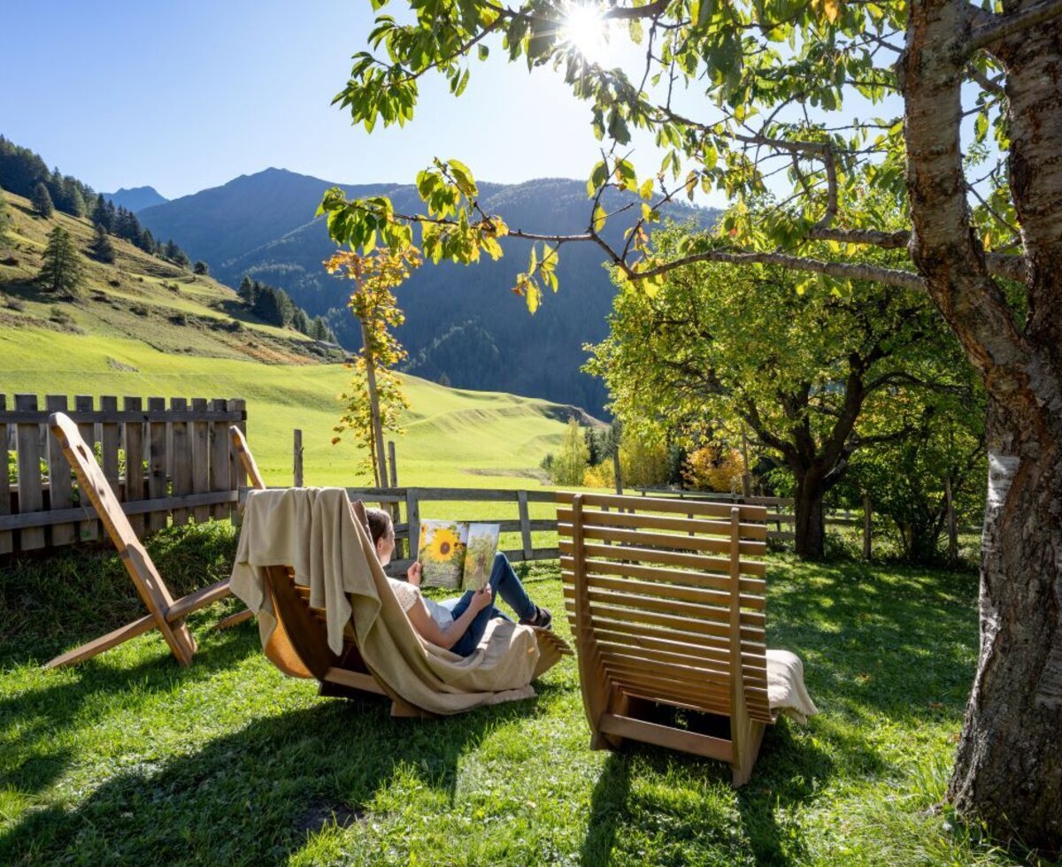 The farmhouse's sunny garden featuring comfortable wooden lounge chairs and a wonderful view of the surrounding mountains.