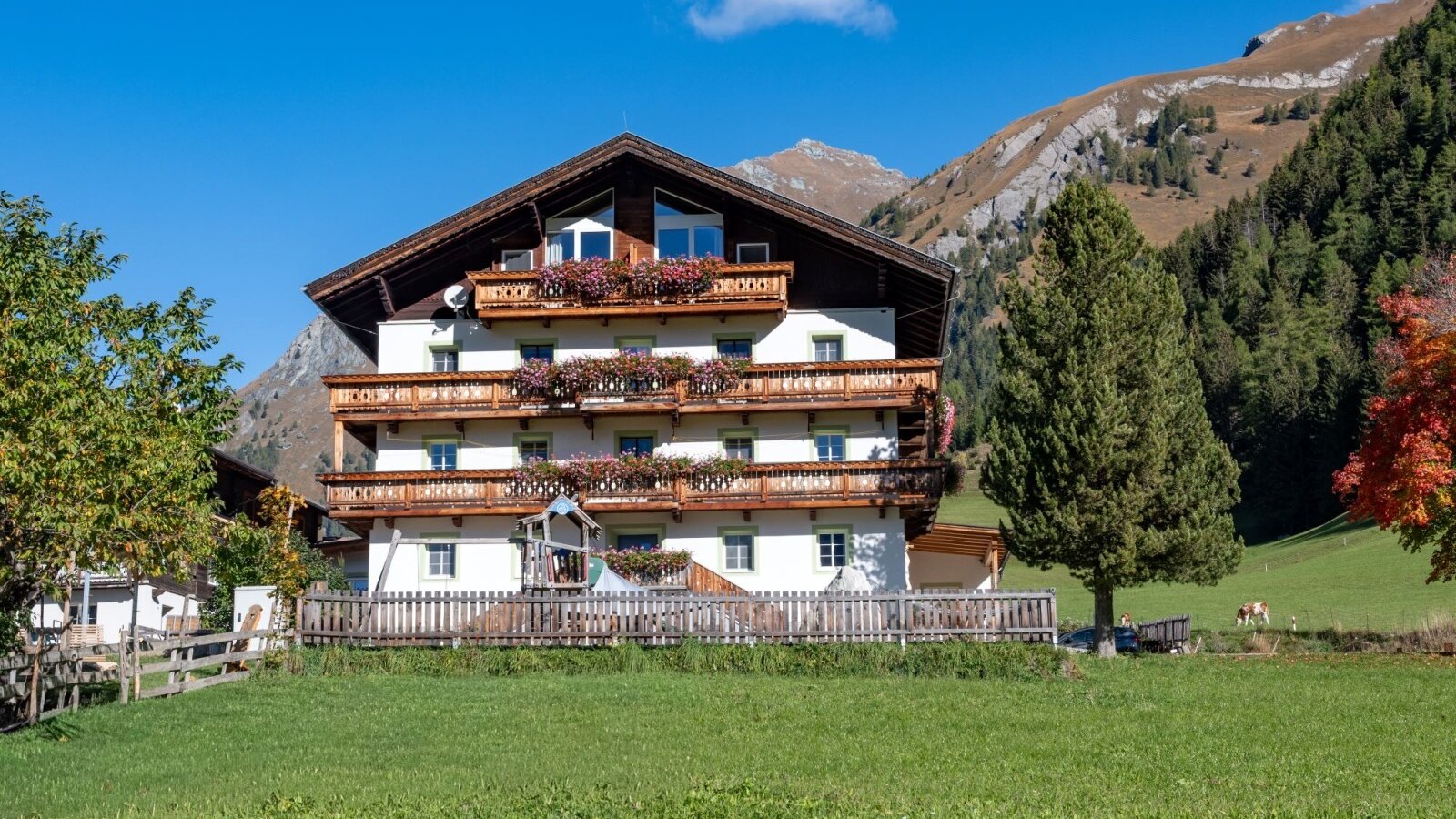 The inviting Bauernhof with flower-adorned wooden balconies set against the scenic backdrop of the East Tyrolean mountains.