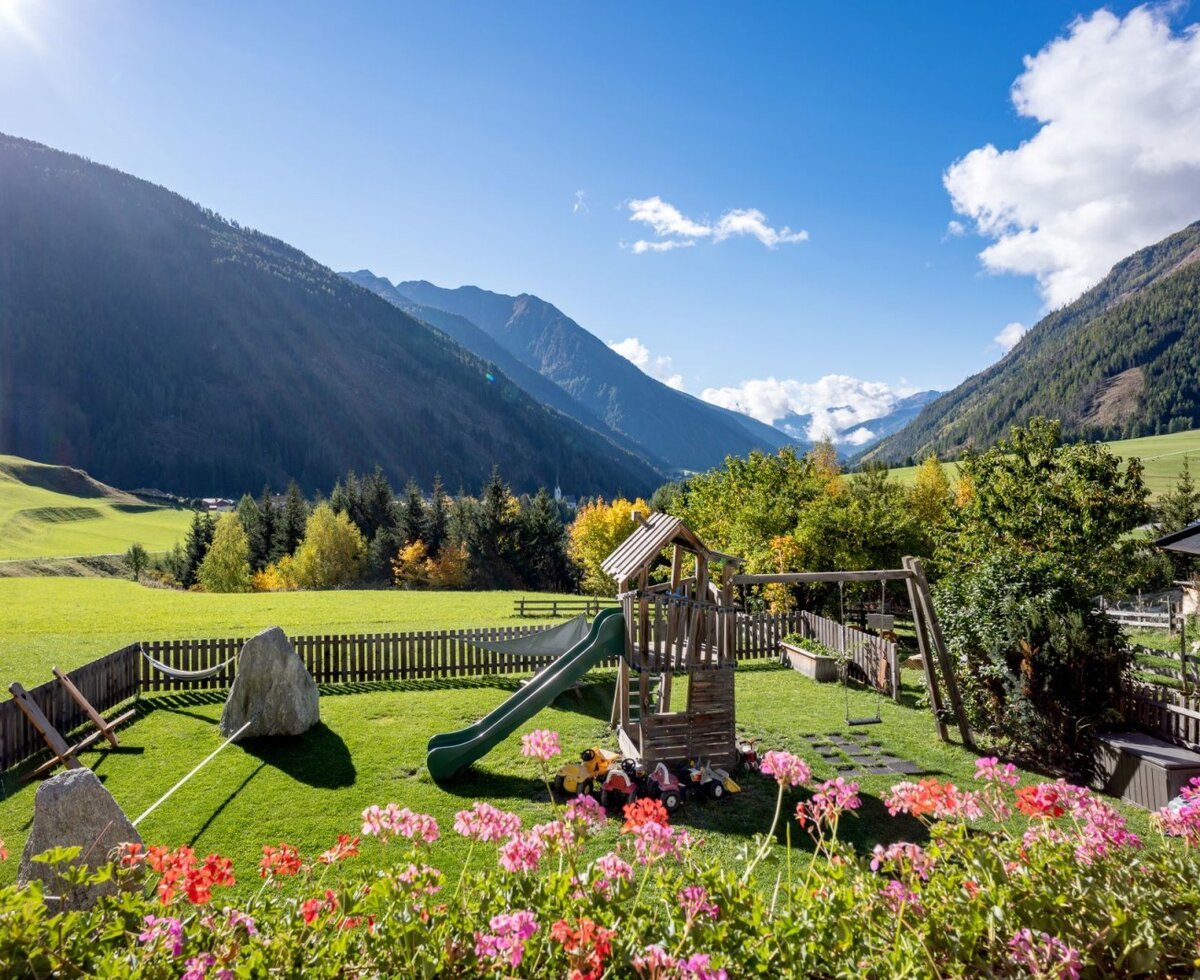 The Bauernhof's inviting children's playground with a slide and swing, set against an idyllic mountain panorama.