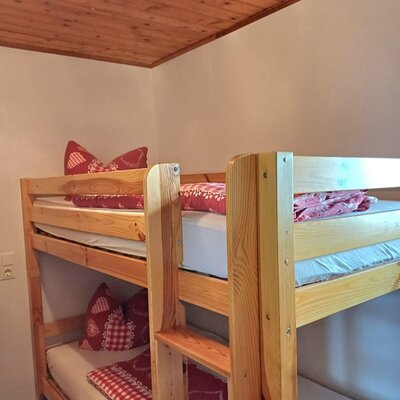 Wooden bunk bed with red and white bedding in the Alpine Hut.