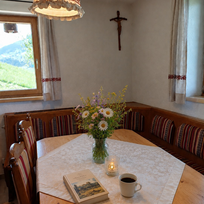 A cozy dining corner in the Chalet featuring a traditional wooden bench, fresh wildflowers, and an inviting table setting.