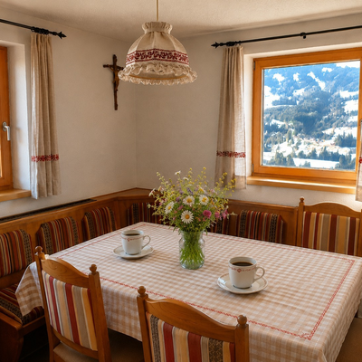 Cozy dining area of the hut featuring a traditional wooden corner bench and scenic views of the snow-covered mountains.