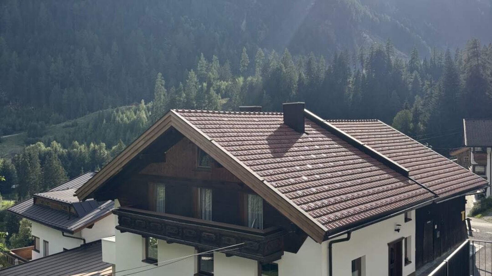 The inviting apartment building set against a scenic mountain backdrop, featuring a small garden playground.