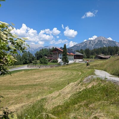 The farmhouse in a rural setting with expansive meadows and mountain views.