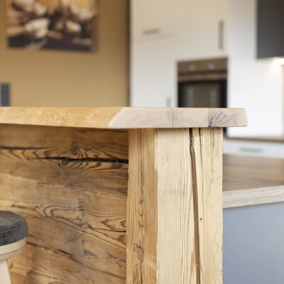 The farm house kitchen includes a wooden breakfast bar with a stool, facing modern kitchen appliances.