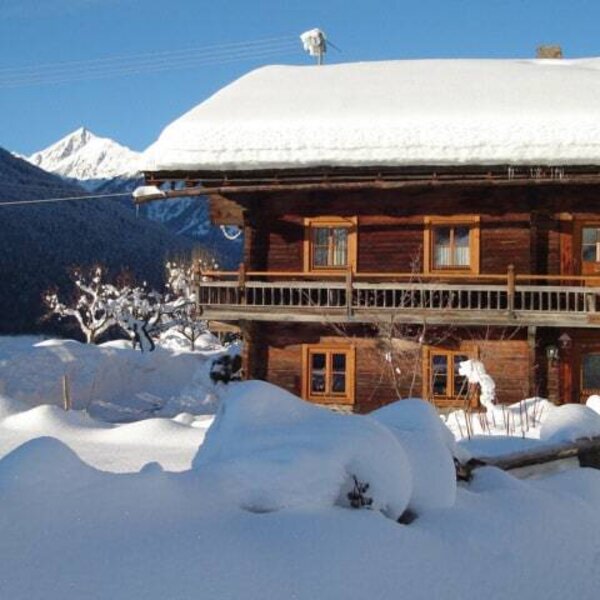 The old wooden farmhouse with a balcony, surrounded by snow and mountains. The old wooden farmhouse with a balcony, surrounded by snow and mountains.