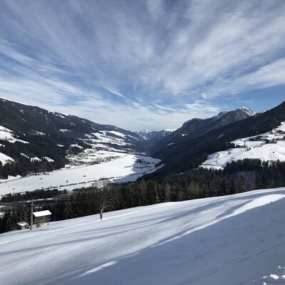 The view from the Farm House across a snow-covered mountain valley with a village and ski slopes.