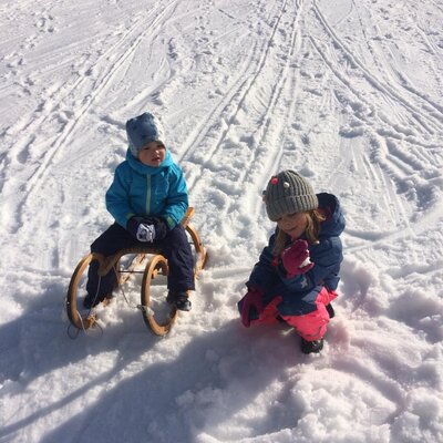 Children playing on a sled in the snow, an activity available for guests of the Farm House.