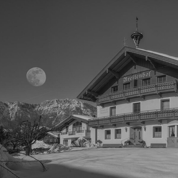 The Farm House exterior, featuring traditional wooden balconies, set against snow-covered mountains.