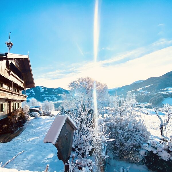 The exterior of the Farm House, featuring traditional wooden balconies and shutters, set against a snow-covered mountain landscape.