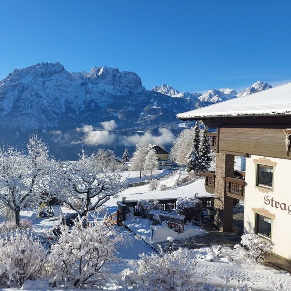 The Farm House exterior in winter, featuring a snow-covered children's playground and views of the surrounding mountains.