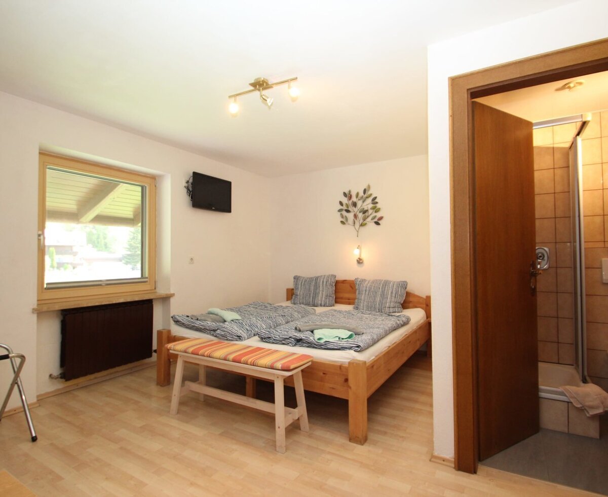 Double bedroom in the Farm House featuring a wall-mounted television, a window, and an adjoining bathroom with a shower and WC.
