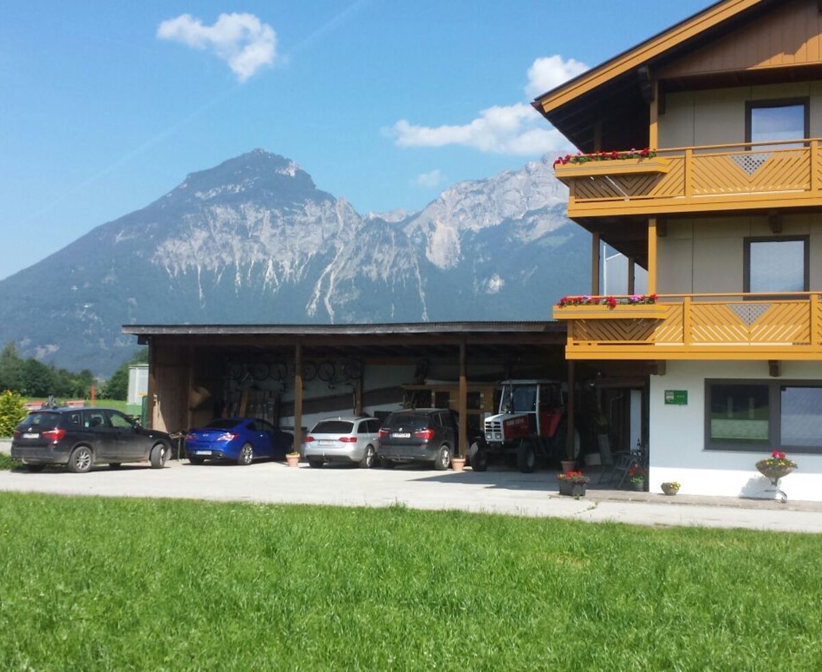 The Farm House exterior features balconies, a covered parking area, and a view of the mountains.