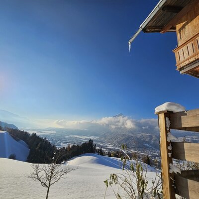 The farmhouse exterior with its wooden balcony overlooking the snowy Inn Valley and the town of Schwaz.