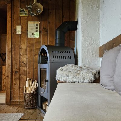 A cozy living area in the farmhouse with a rustic wood-burning stove and an inviting seating bench.