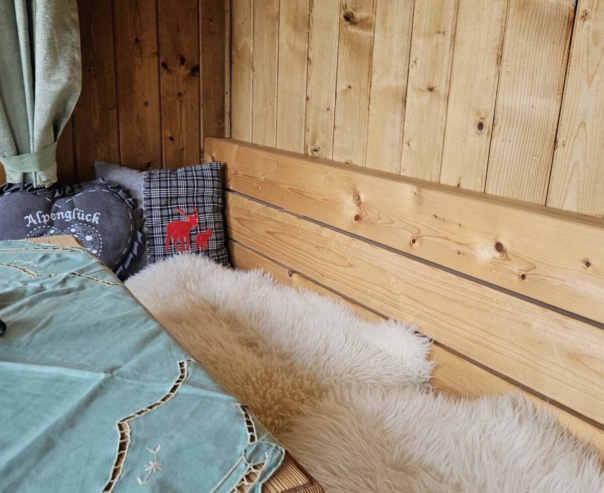 Cozy seating area in the holiday home featuring rustic wood paneling, soft sheepskin throws, and decorative cushions.
