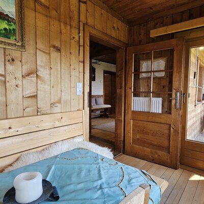 A rustic room featuring traditional wood paneling and direct access to a sunny balcony.
