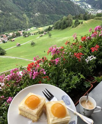 The farmhouse's balcony offers a scenic view of the lush green hills and mountains, perfect for enjoying a coffee.