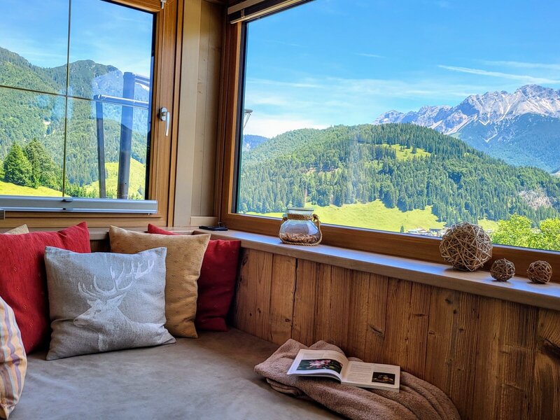 A comfortable window seat in the Farm House, featuring cushions and direct views of the surrounding mountains and forests.