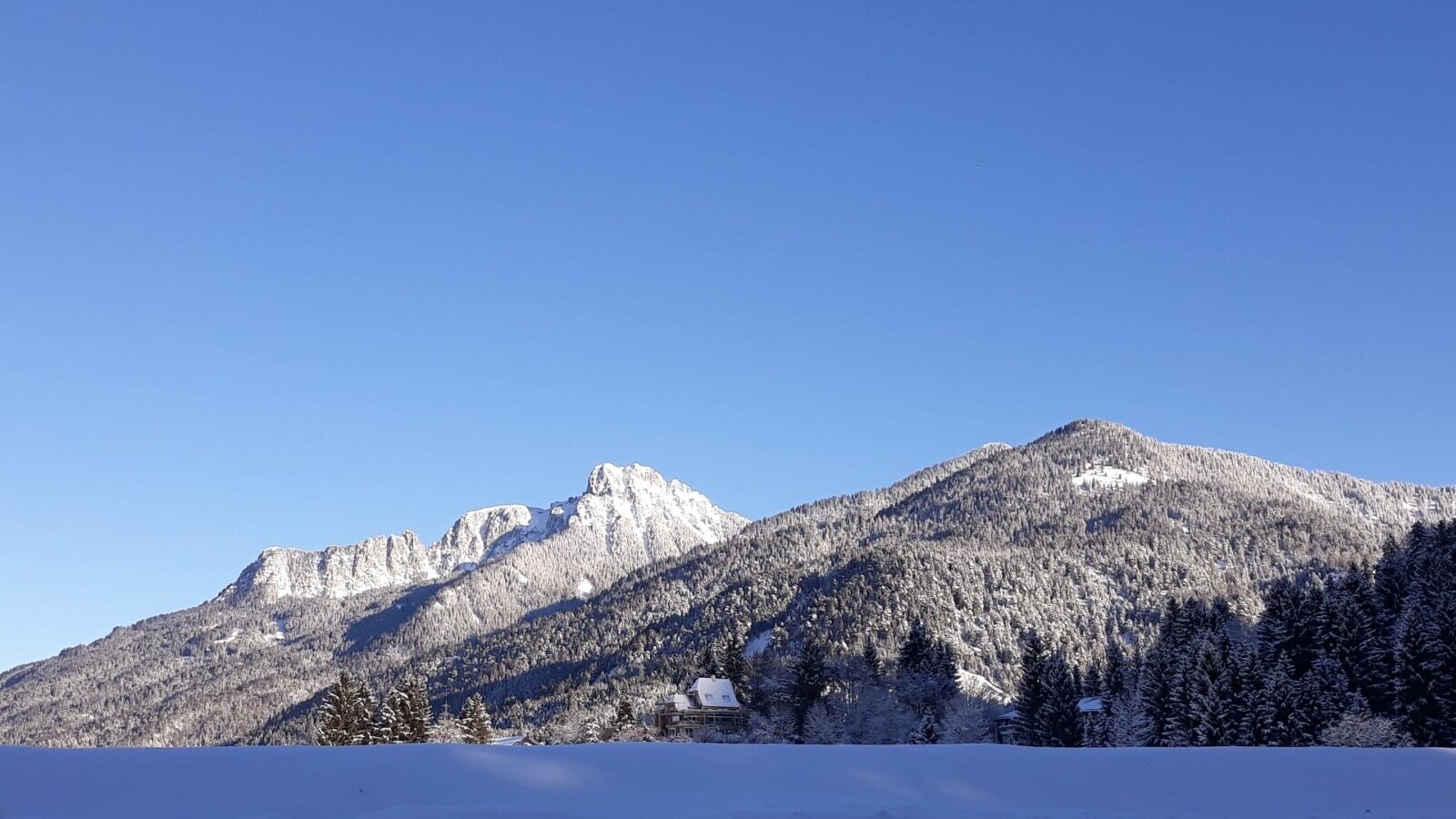 Snow-covered mountains and evergreen trees define the winter landscape surrounding the Farm House.
