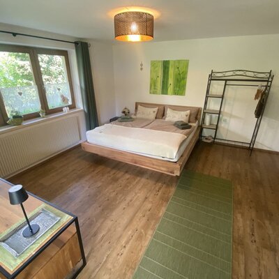 A cozy bedroom at the farmhouse featuring an inviting wooden double bed, stylish furnishings, and warm color accents.