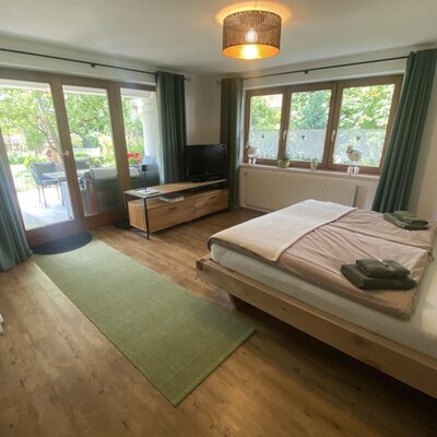 A bright and cozy bedroom in the farmhouse featuring a double bed, flat-screen TV, and direct access to the sunny terrace.