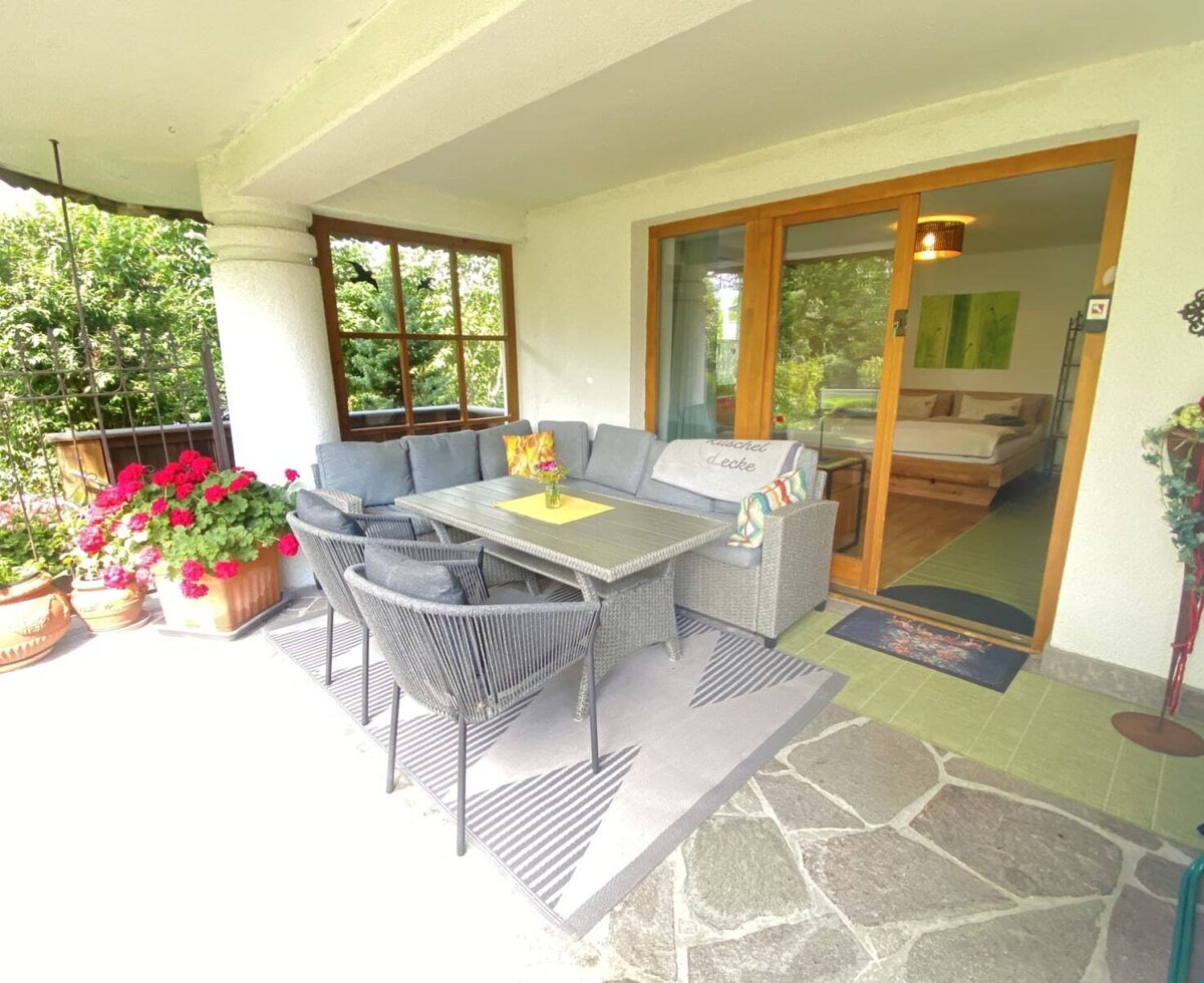 The farmhouse's inviting terrace featuring a comfortable seating area, vibrant flowers, and direct access to the bedroom.