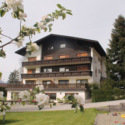 The farmhouse exterior, featuring multiple balconies, a green lawn, and a children's play area.